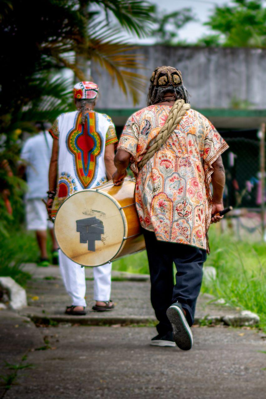 Músicos do Clube de Bambas, caminhando com instrumentos no alto do Monte Serrat, em Santos.